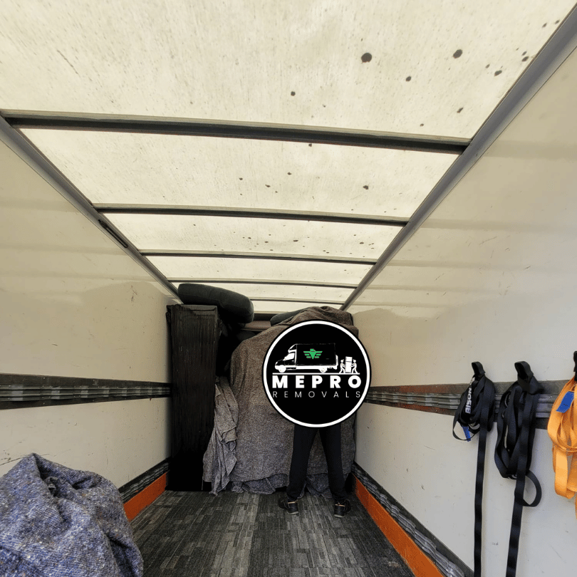 The Mepro Removals team, expert Piano Movers Manchester, carefully securing an upright piano with protective blankets.